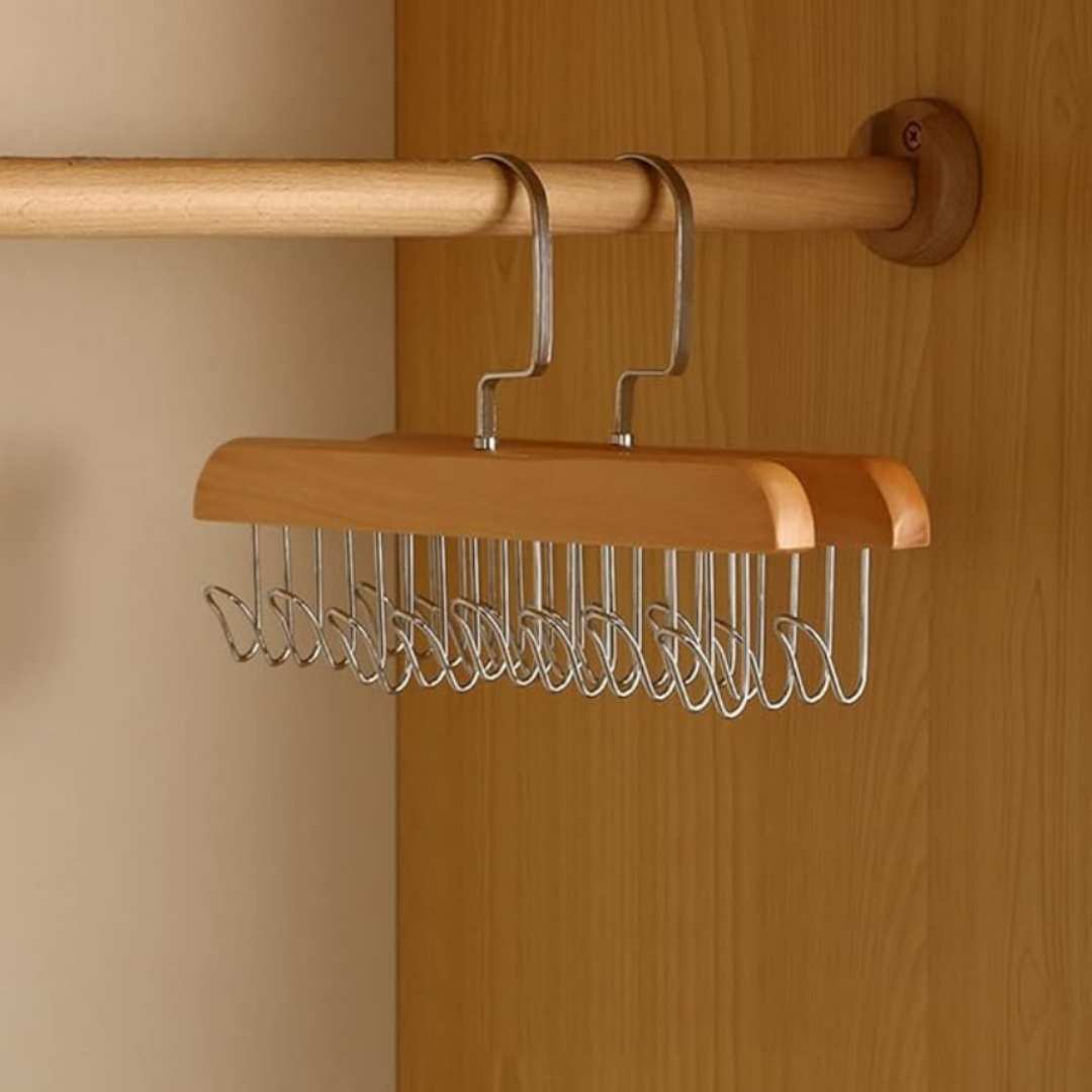 Wooden hanger with metal hooks attached to a wooden rod against a wooden wall.