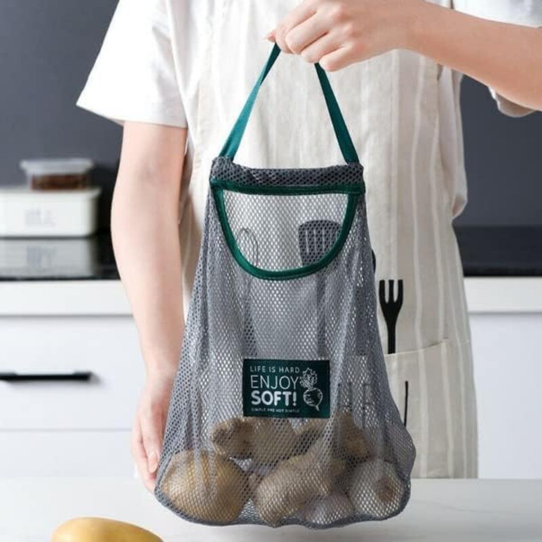 Person holding a mesh produce bag with vegetables, branded 'Enjoy Soft'.