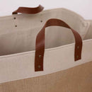Beige tote bag with brown leather handles on a light gray background