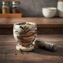 Marble-patterned mortar and pestle on a wooden surface with spices in the background