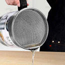 Person using a metal strainer to pour liquid from a can onto a wooden surface.