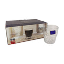 Clear glass with blue label next to its packaging on a white background