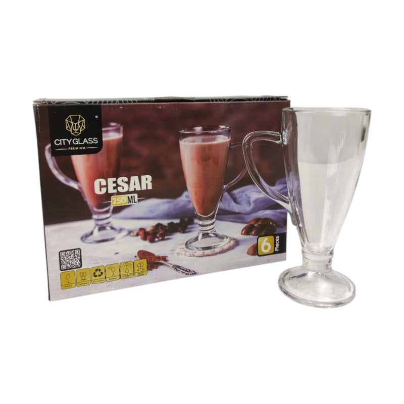 Clear glass mug with red liquid next to its packaging on a white background