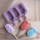 Purple bunny-shaped popsicle mold with three colorful popsicles on a light background