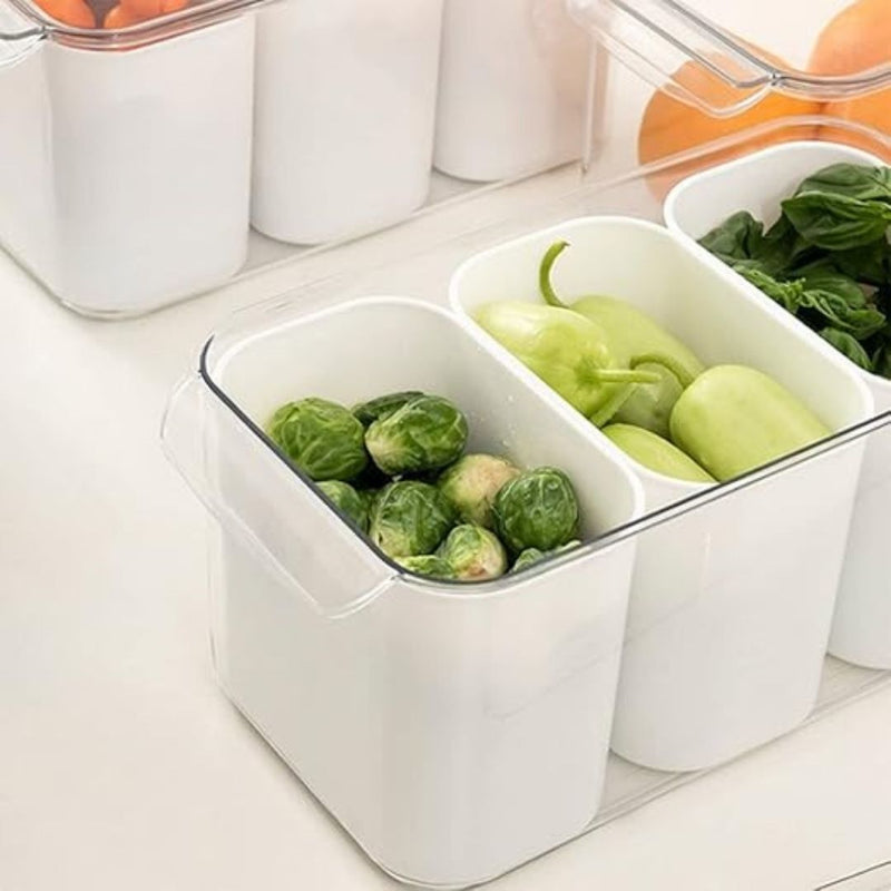 White food storage container with compartments filled with green vegetables on a white surface.