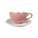 Pink teacup with gold handle on a white saucer against a white background