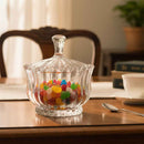 Clear glass candy dish with colorful candies on a wooden table.