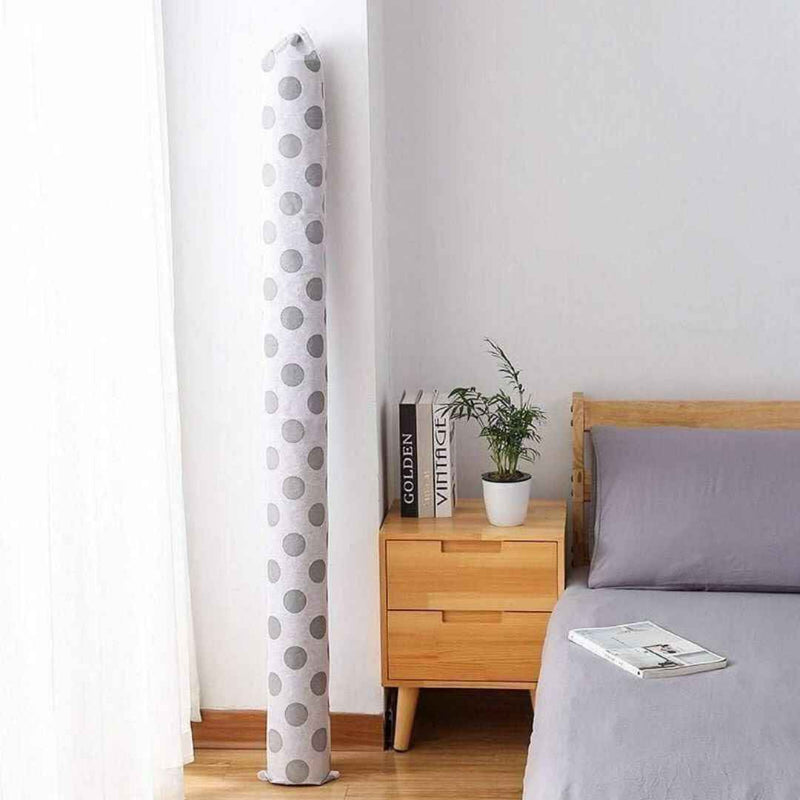 Tall cylindrical polka dot curtain against a white wall with a bed and nightstand in the foreground.