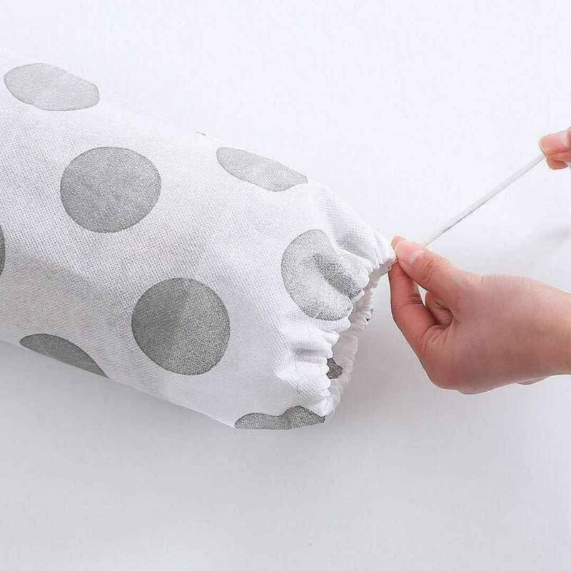 Gray polka dot fabric being stretched over a cylindrical object with a hand holding a white stick.