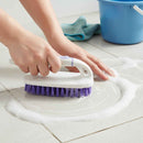 Person cleaning a tiled floor with a scrub brush and blue bucket in the background