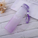 Purple water bottle with 'Hello Master' text on a wooden surface with a laptop and flowers.