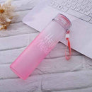 Pink water bottle with 'HELLO WORLD' text on a wooden surface with a laptop.