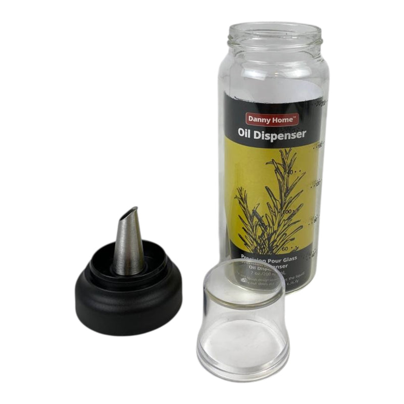 Oil dispenser with black cap and clear glass container on a white background