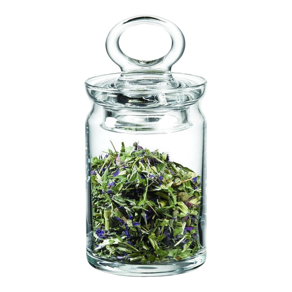 Clear glass jar with a lid filled with green herbs on a white background