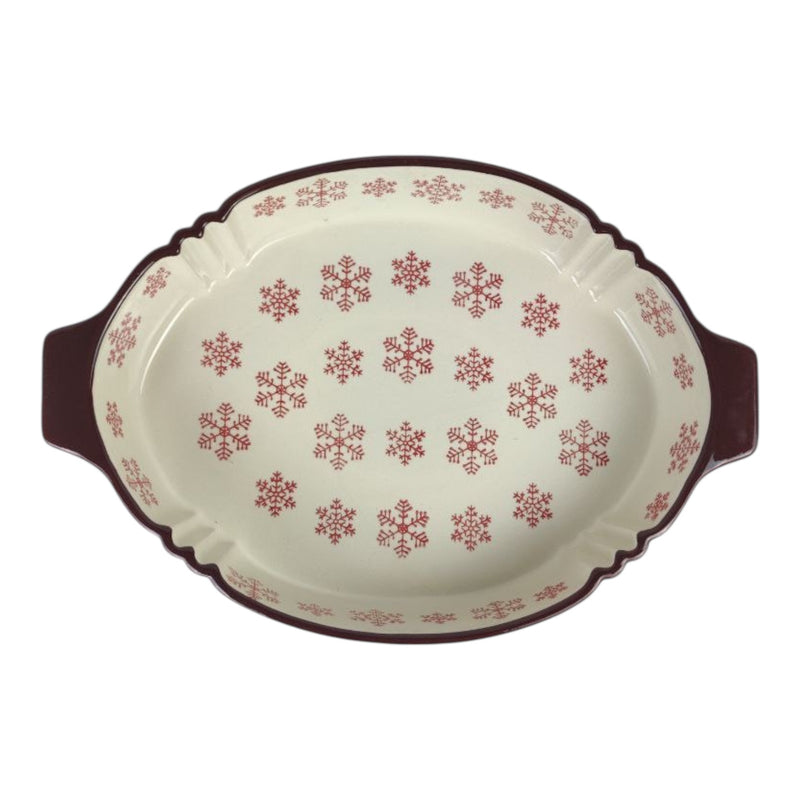 Oval ceramic baking dish with red snowflake pattern on a white background