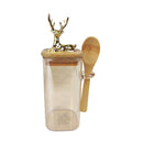 Clear glass jar with wooden lid and spoon, featuring a gold deer figurine on a white background