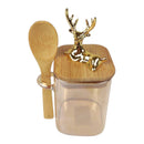 Clear container with gold deer design lid and wooden spoon on a white background