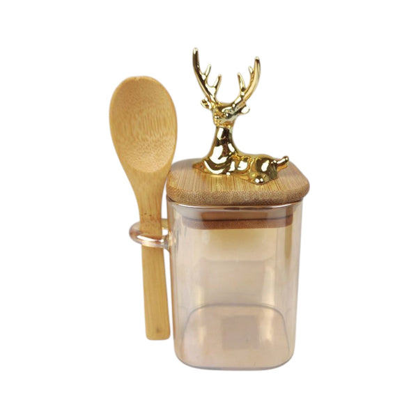 Glass jar with bamboo lid and spoon, featuring a deer design on the lid, on a white background.