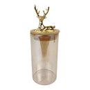 Clear tumbler with a gold deer figurine on top against a white background