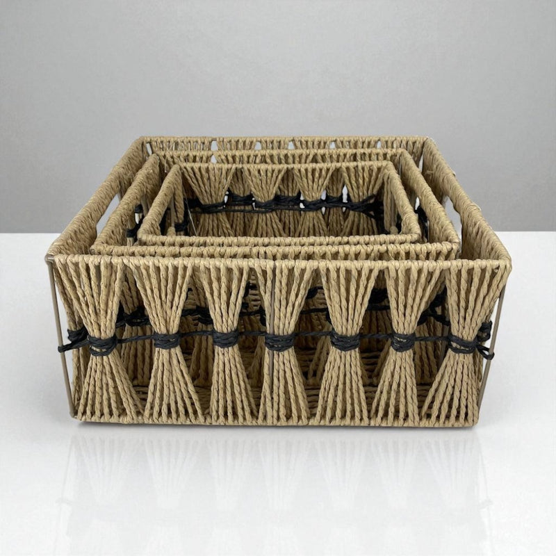 Set of woven baskets with black straps on a white surface and gray background