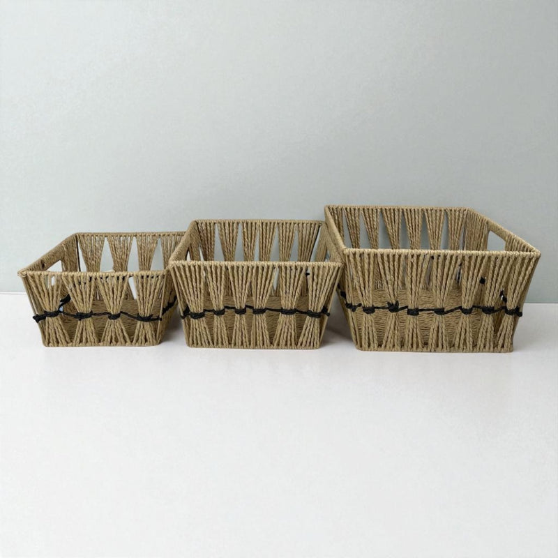 Three woven baskets of different sizes on a white surface with a light gray background