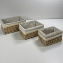 Three woven baskets with gray fabric interiors on a white surface