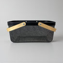 Black basket with woven design and wooden handles on a gray background