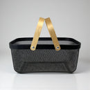 Black mesh shopping basket with gold handles on a gray background