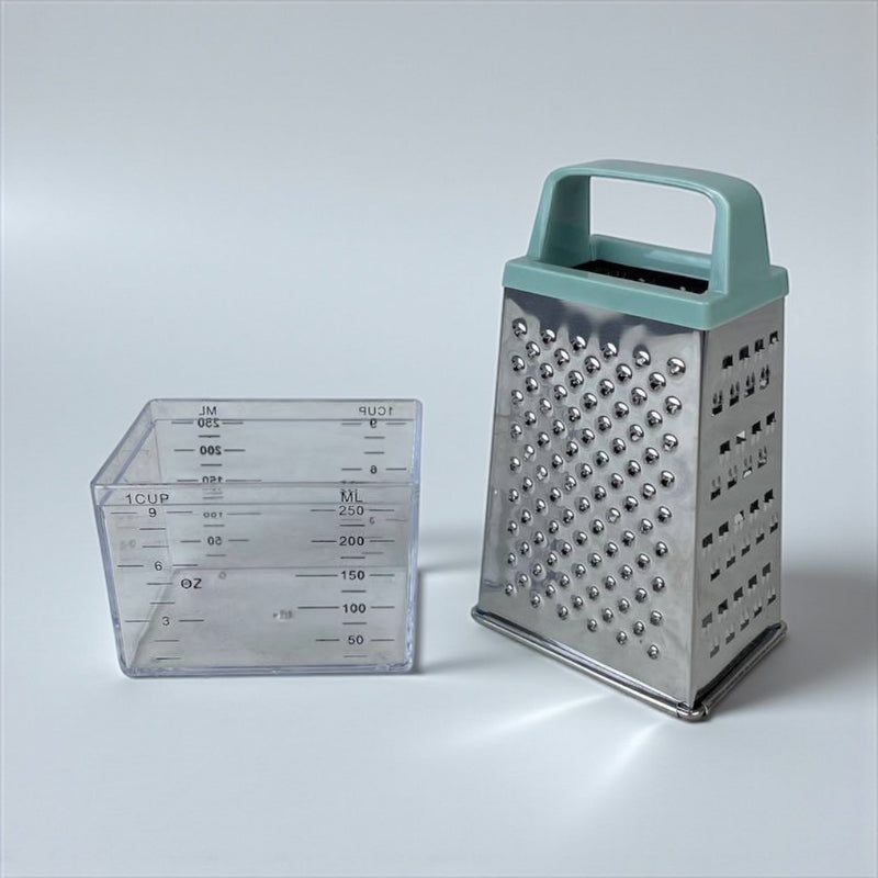 Metal box grater with a handle next to a clear measuring cup on a light gray background available at cupindy.com