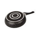 Black speckled frying pan with a silver circular design on a white background