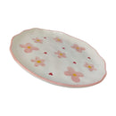 Oval ceramic dish with pink floral patterns on a white background