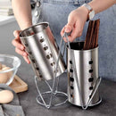 Two metal skewer holders with tongs on a kitchen counter.