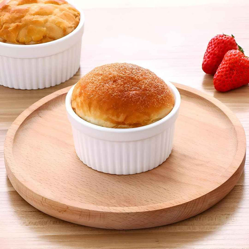 Baked good in a white ramekin on a wooden plate with strawberries in the background available at cupindy.com