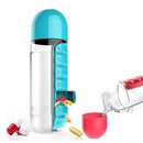 Clear water bottle with blue top and pill compartment, alongside a pink cup and scattered pills on a white background.