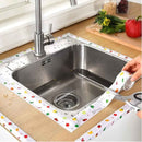 Stainless steel kitchen sink with colorful protective mat on wooden countertop