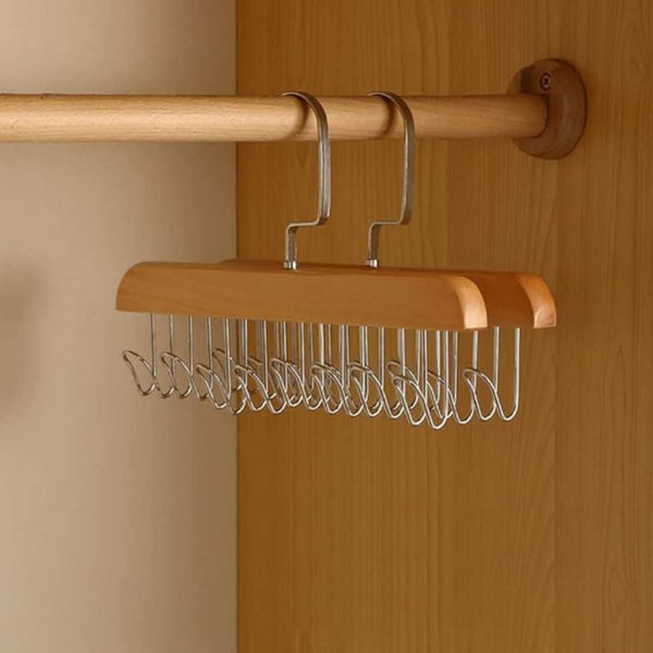 Wooden hanger with metal hooks attached to a wooden rod against a wooden wall.