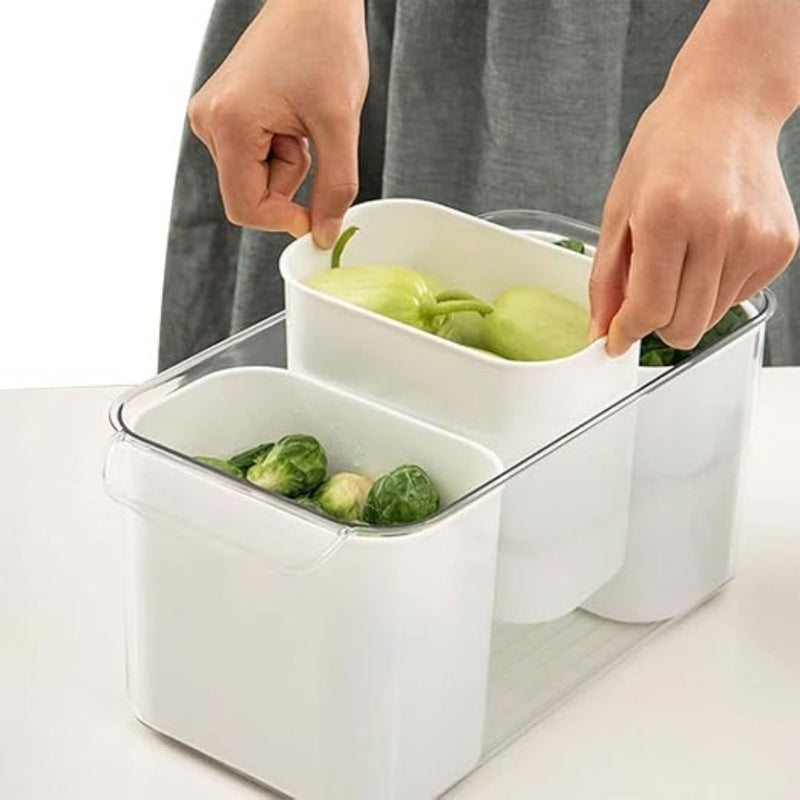 Person using a white vegetable storage container with green vegetables inside on a light surface.