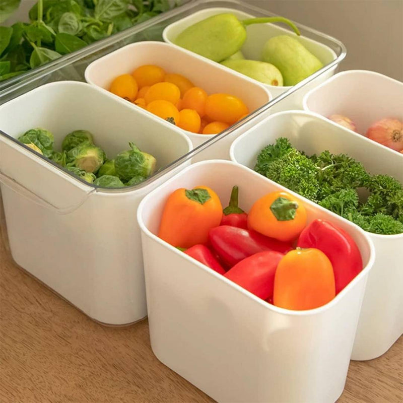White vegetable storage containers with compartments filled with various vegetables on a wooden surface.