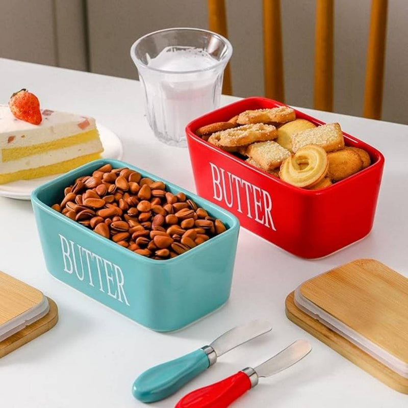 Two containers labeled 'Butter' with one holding seeds and the other holding bread, on a table with a glass of water and dessert.
