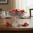 Clear glass fruit bowl filled with berries on a wooden table.