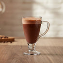 Glass mug filled with a hot chocolate drink on a wooden surface.