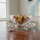 Clear glass fruit bowl with assorted fruits on a wooden table.