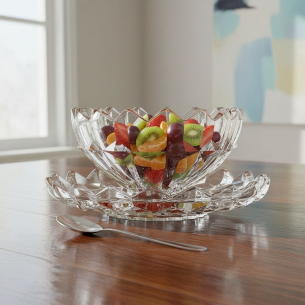Clear glass fruit bowl with assorted fruits on a wooden table.