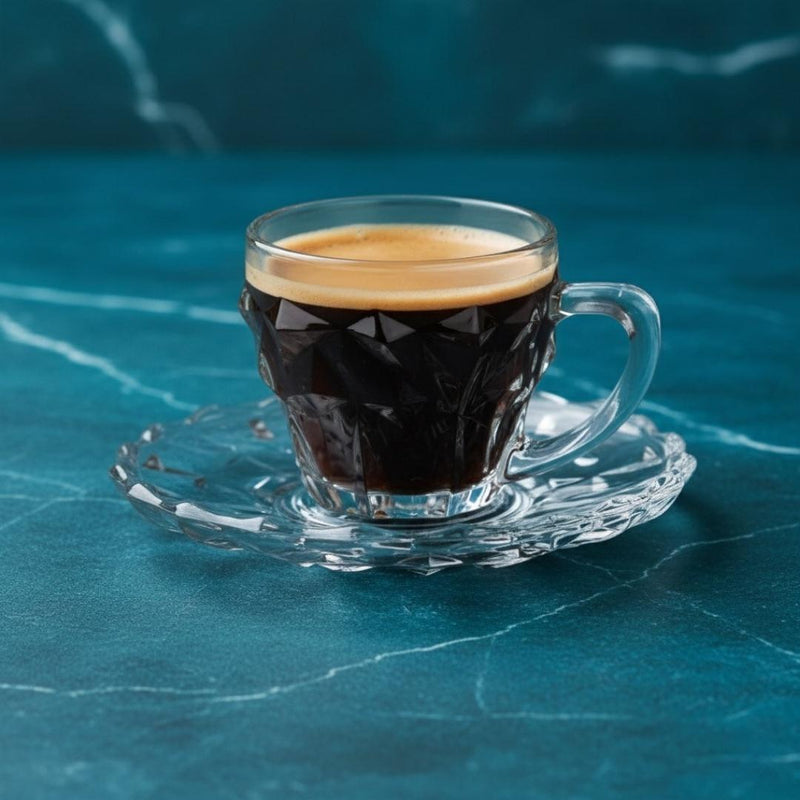 Clear glass cup with espresso on a blue marble surface