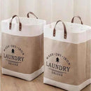 Two laundry bags with 'Wash Dry Iron Laundry Deluxe' text on a wooden floor.