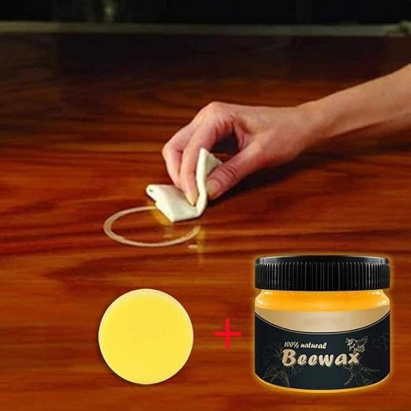 Person applying beewax to a wooden surface with a container of beewax and a yellow sample on the side.