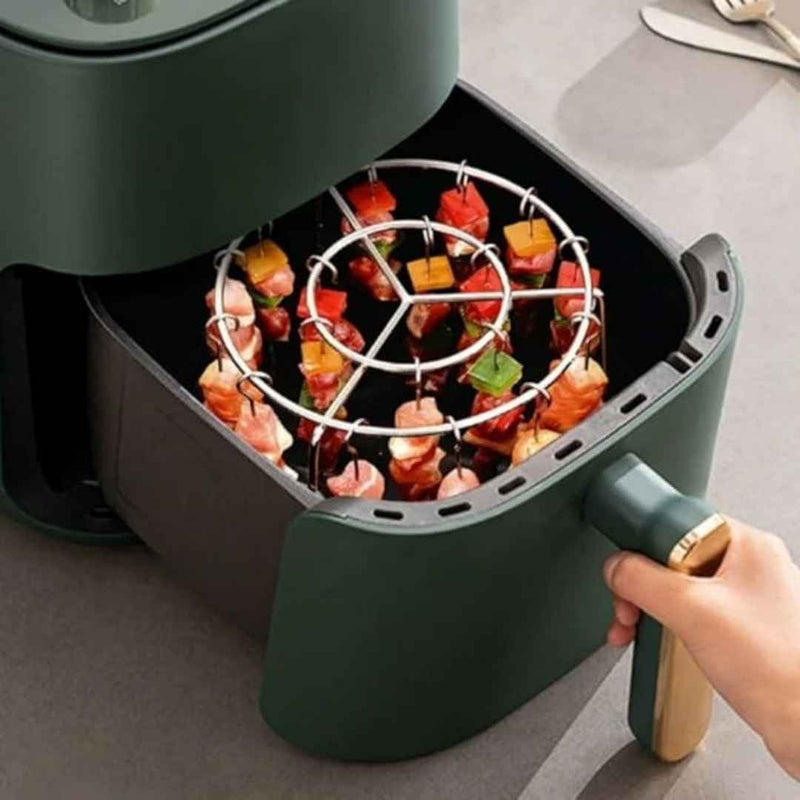 Green air fryer with food being removed, showing a hand holding the handle.