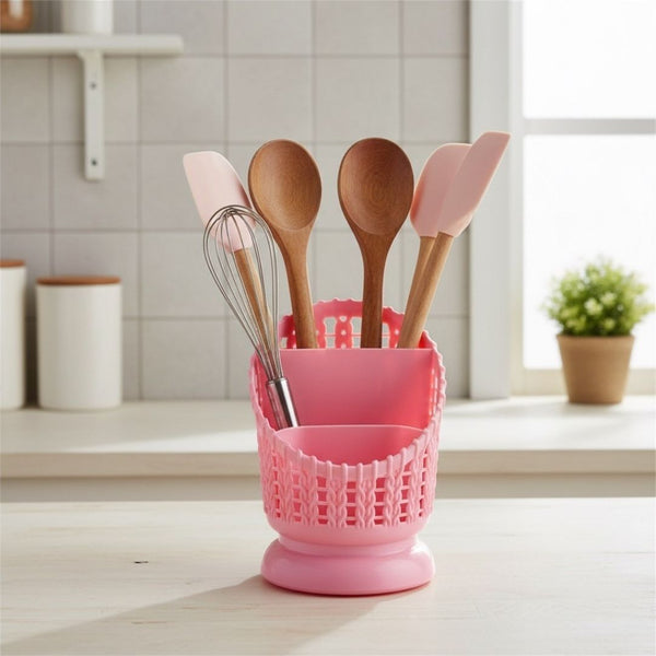 Pink utensil holder with wooden and silicone utensils on a kitchen counter.