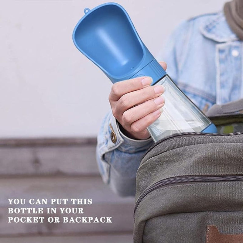 Blue pet hydration bottle held by hand near backpack | Cupindy