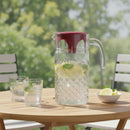Glass pitcher with lemon and mint on a wooden table outdoors